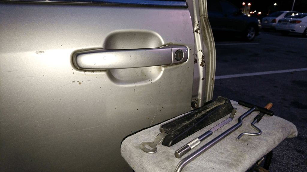 Car door handle with locksmith entry tools nearby