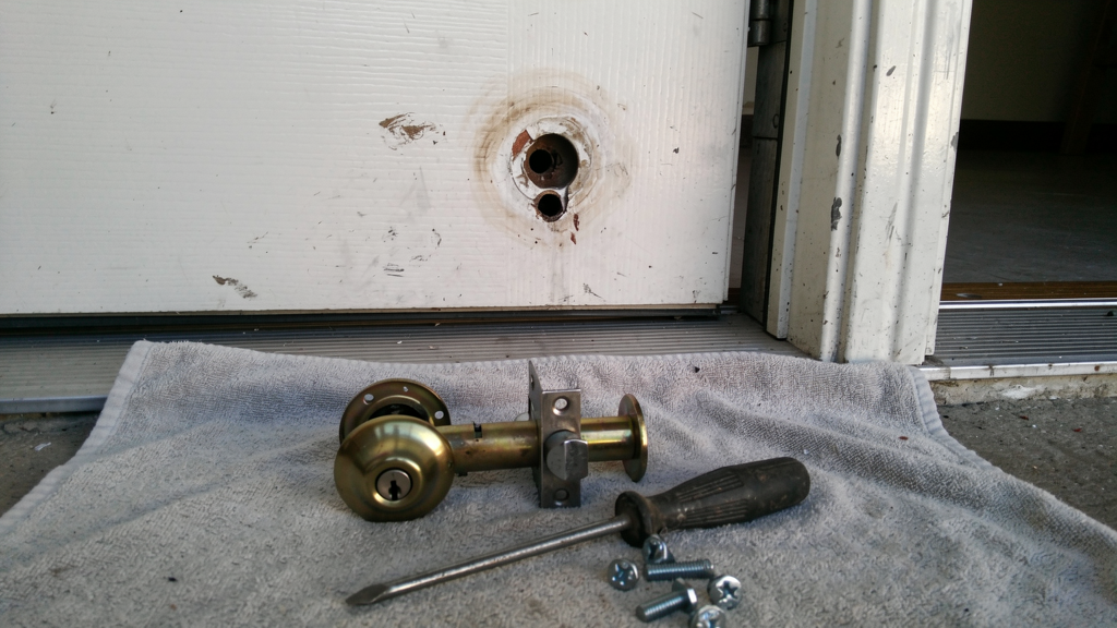 Old lock hardware and a new deadbolt assembly beside a residential door