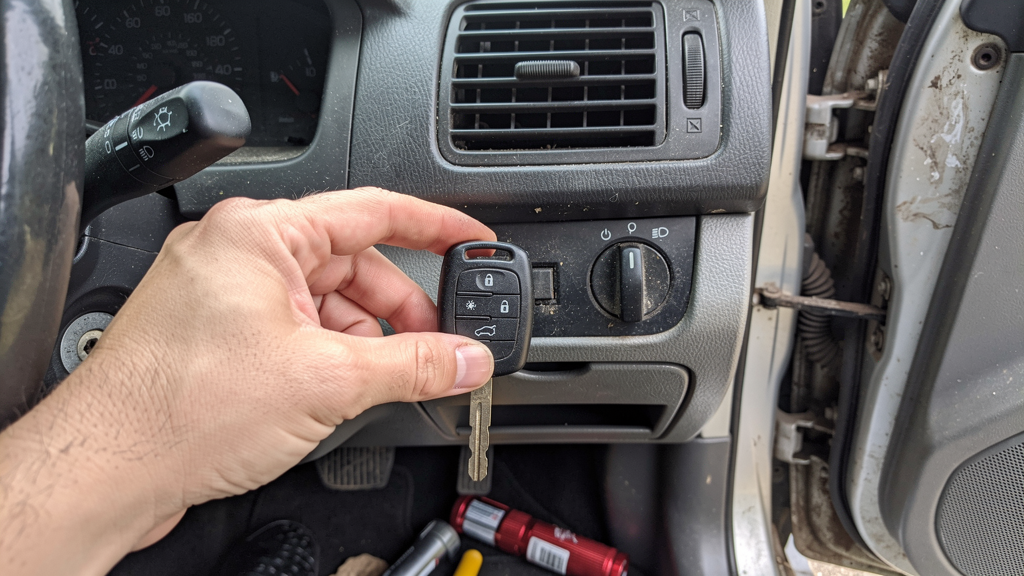 Dead key fob and mechanical key beside a vehicle steering column