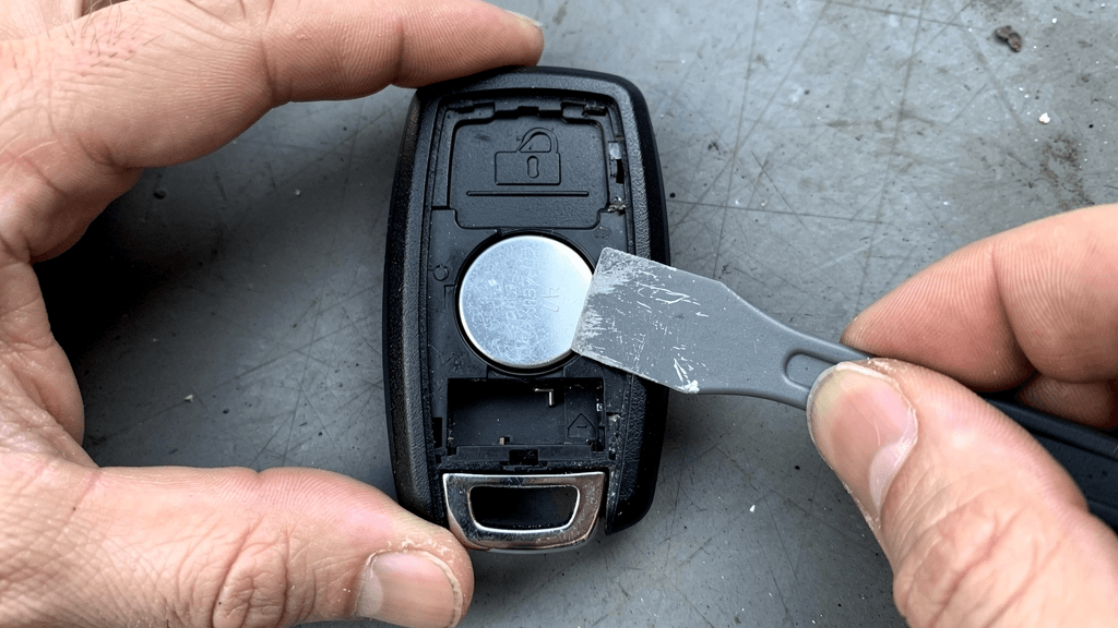 Technician lifting the coin-cell battery from an open key fob